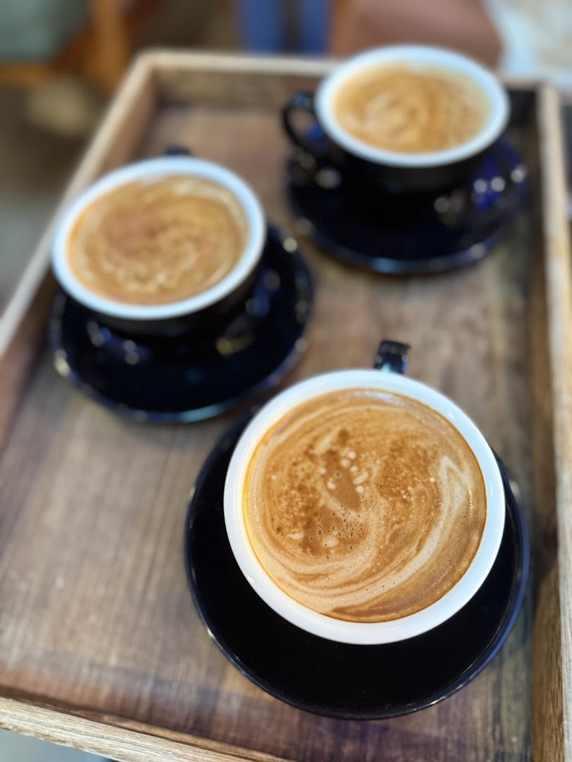 Three cups of coffee with latte art served on a rustic wooden tray.