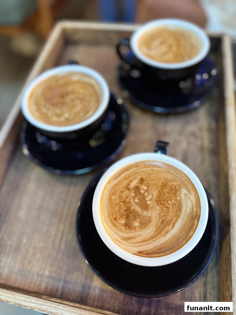 Three cups of coffee with latte art served on a rustic wooden tray.
