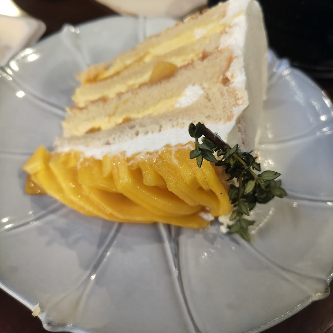 A delectable slice of mango cake with cream and fresh mango slices on a decorative plate.