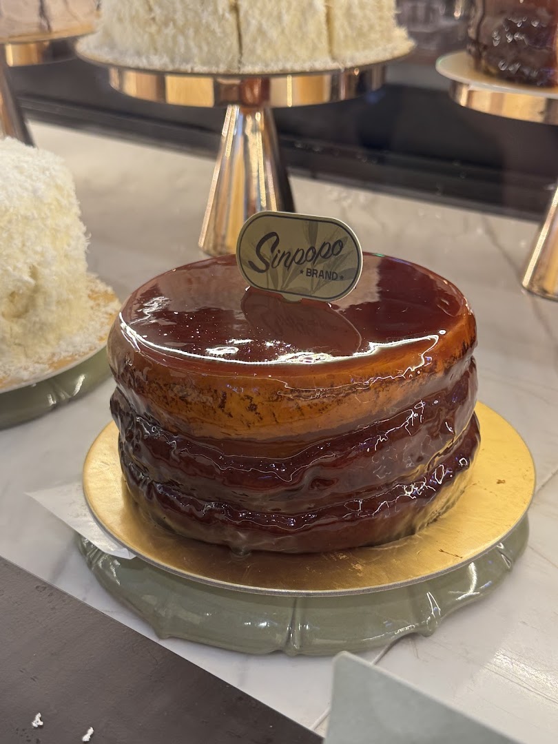 A delicious-looking cake with a glossy caramel glaze and a 'Sinpopo Brand' tag in a display.
