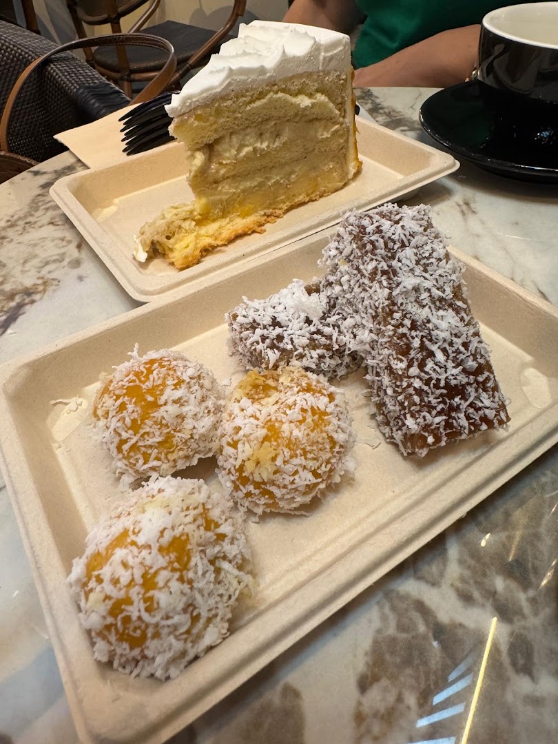 A slice of cake and traditional coconut-dusted desserts served on eco-friendly trays.