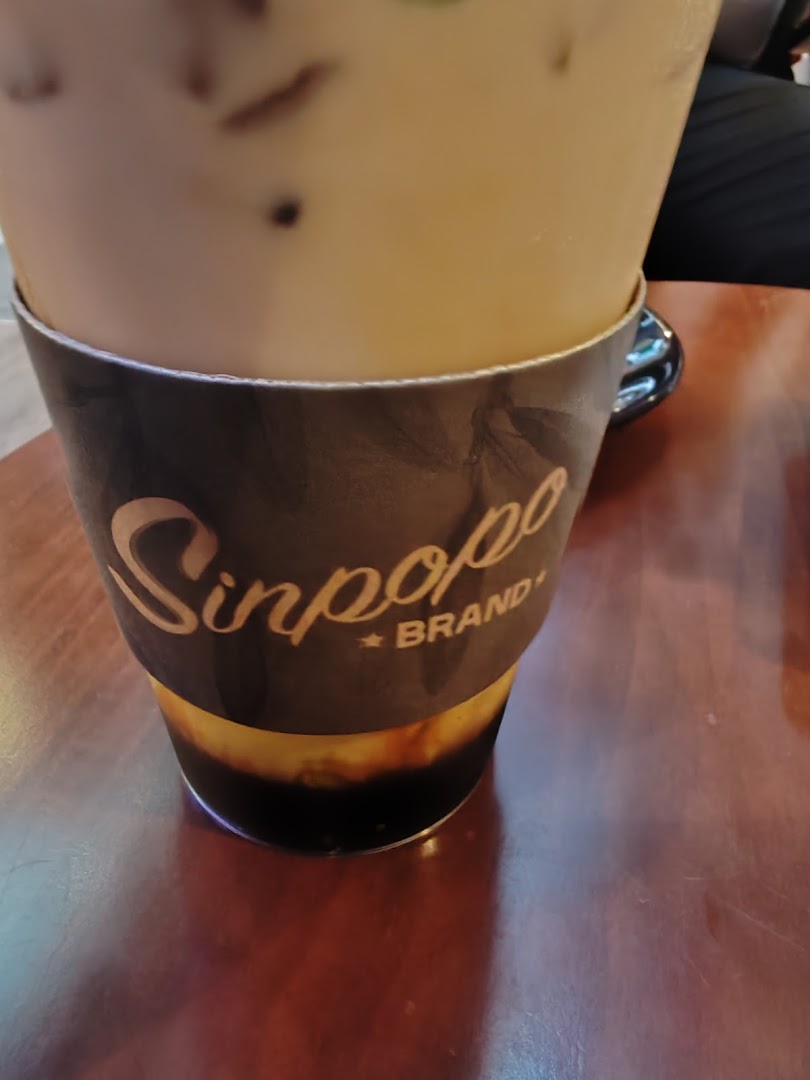 A close-up of an iced beverage from Sinpopo Coffee, featuring its branded sleeve.