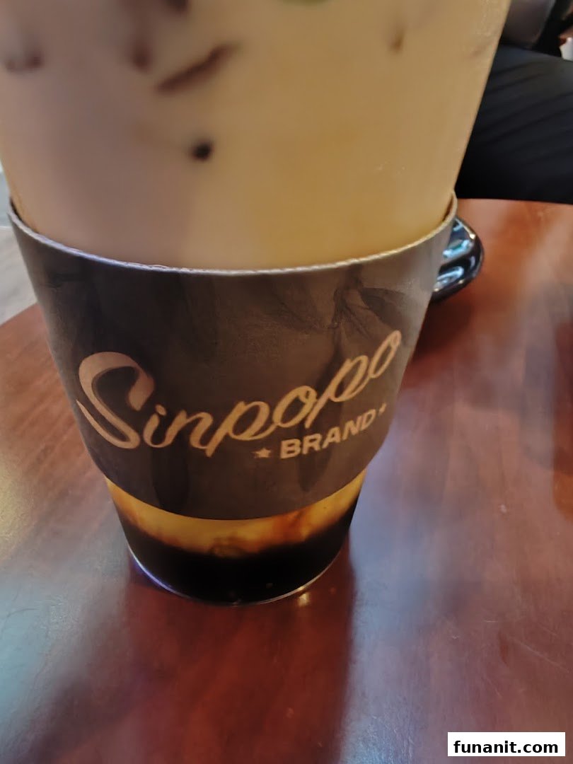A close-up of an iced beverage from Sinpopo Coffee, featuring its branded sleeve.