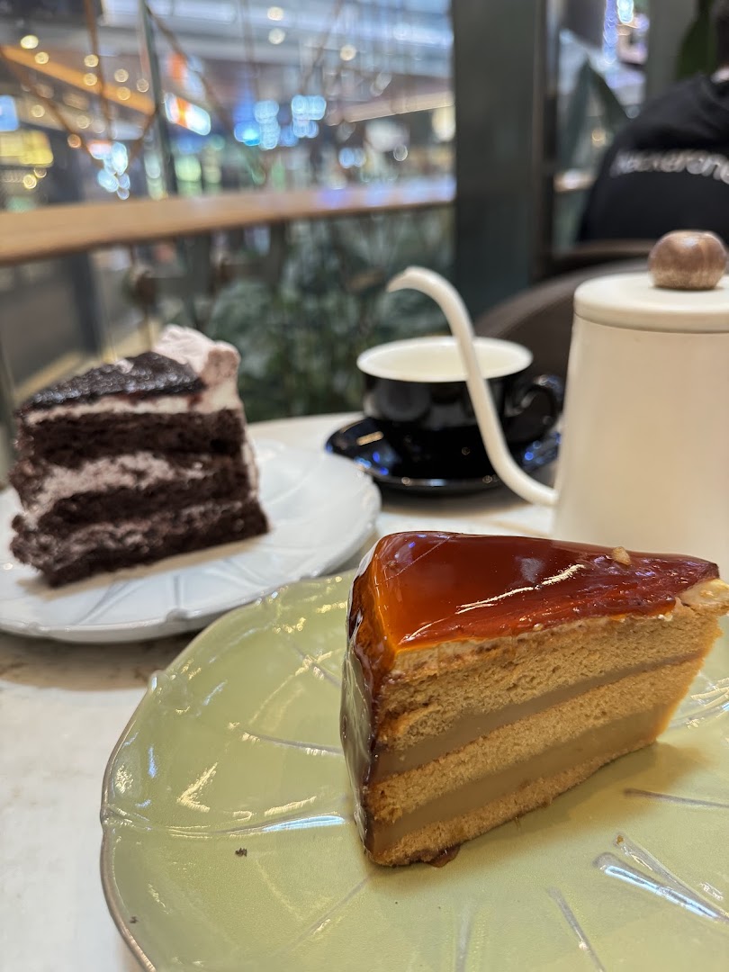 Two delicious cake slices and a coffee cup on a table, with a blurred background of the mall.