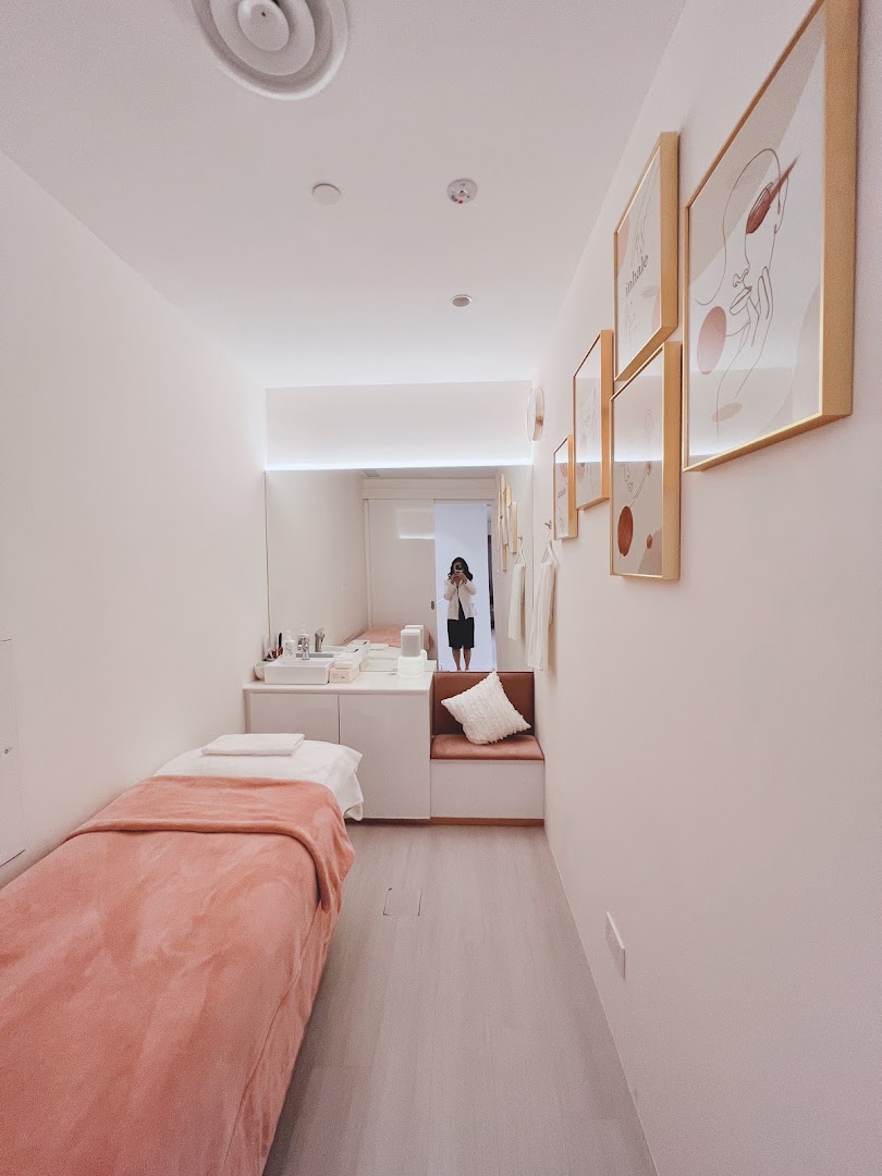 A clean, modern treatment room with a bed, vanity, and minimalist decor.