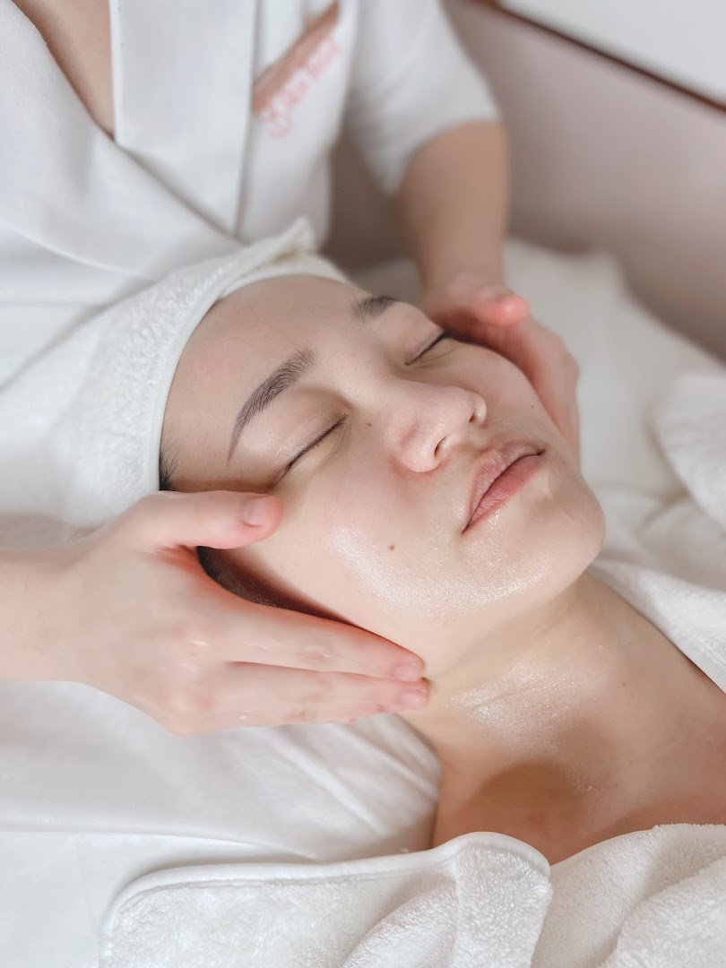 A person receiving a relaxing facial treatment from a therapist at Skin Belief.