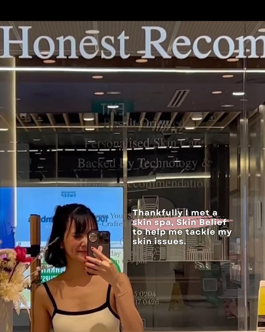A person takes a selfie in front of the Skin Belief shop entrance, showcasing its modern facade.