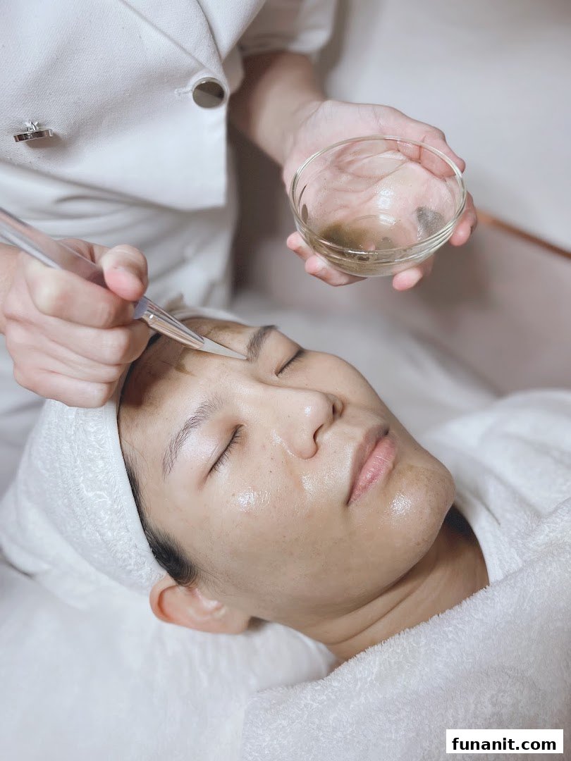 A person receiving a facial treatment with a mask being applied by a therapist.