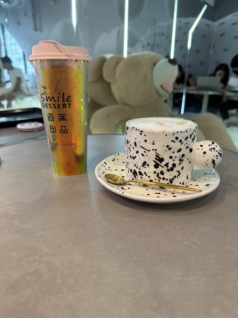 Two unique drinks on a table with a large teddy bear in the background at Smile Dessert.