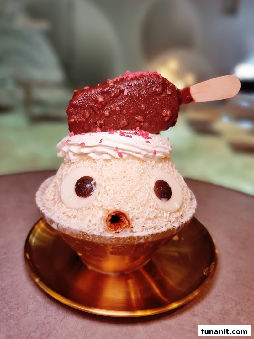 A cute character-themed shaved ice dessert topped with whipped cream, sprinkles, and a chocolate ice cream bar.