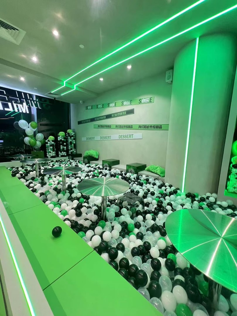Interior of Smile Dessert with a large ball pit, neon green lighting, and tables for a unique dining experience.