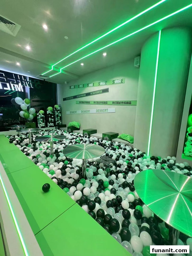 Interior of Smile Dessert with a large ball pit, neon green lighting, and tables for a unique dining experience.