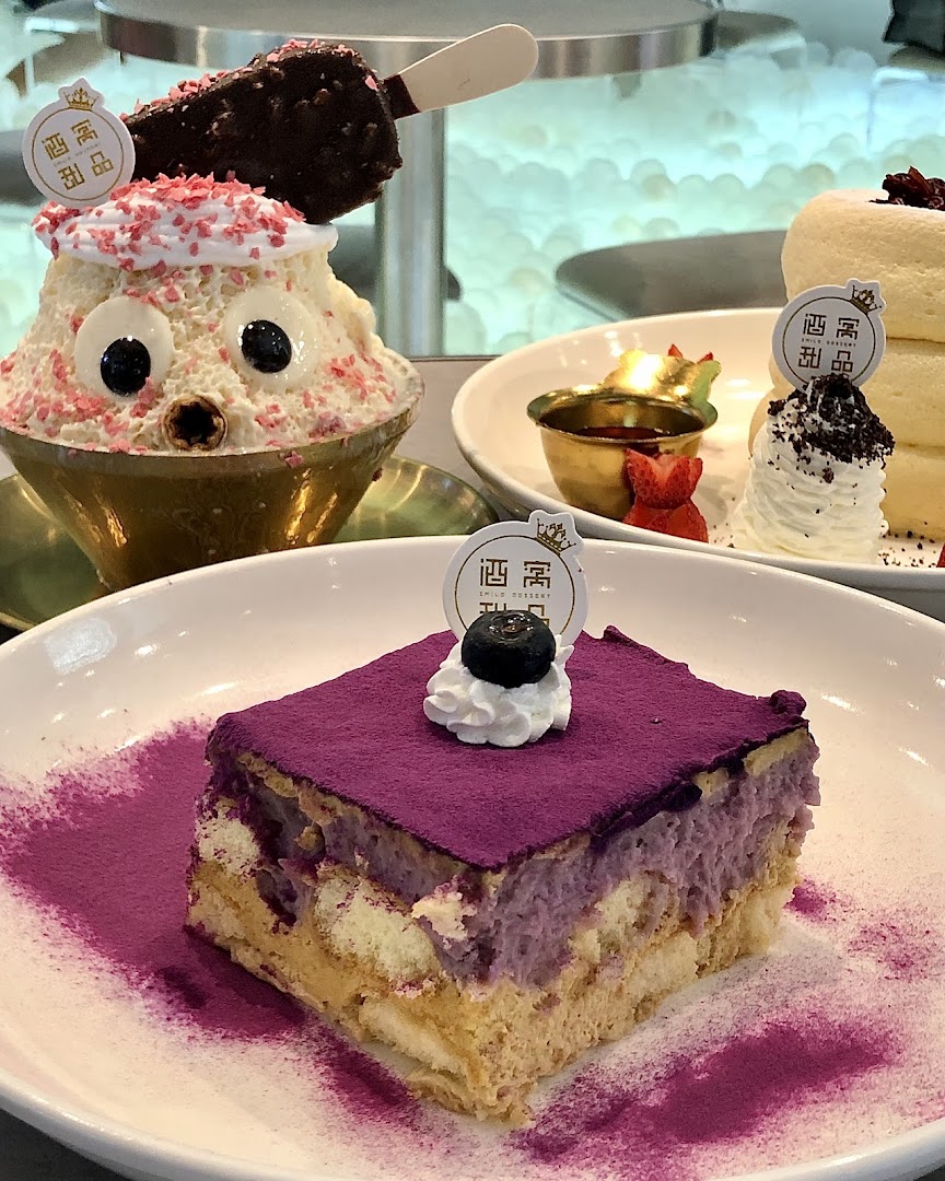 A vibrant display of Smile Dessert's offerings, including a purple cake, a whimsical shaved ice, and fluffy pancakes.