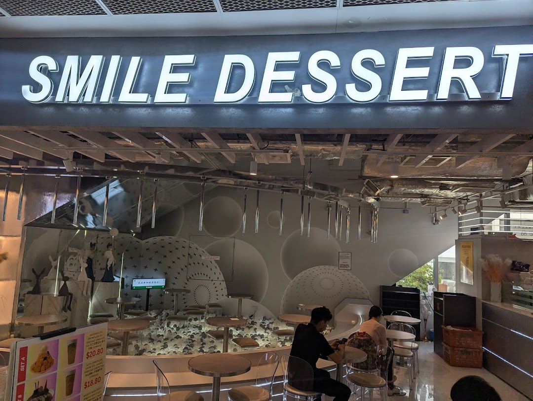 The illuminated 'Smile Dessert' shop sign above its entrance, with customers inside.