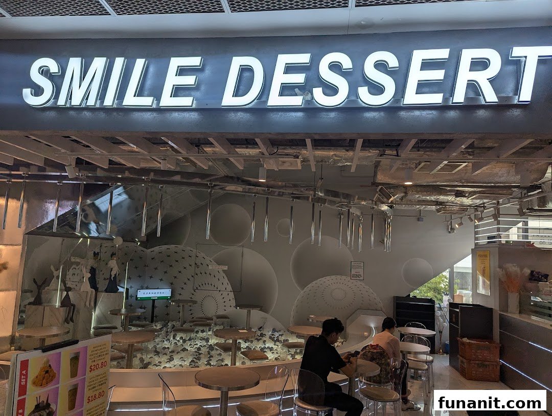 The illuminated 'Smile Dessert' shop sign above its entrance, with customers inside.