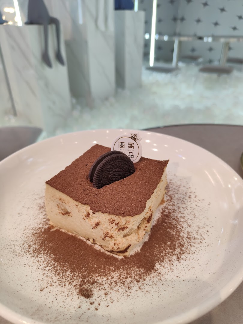 Decadent tiramisu-style dessert with cocoa and an Oreo on a white plate.