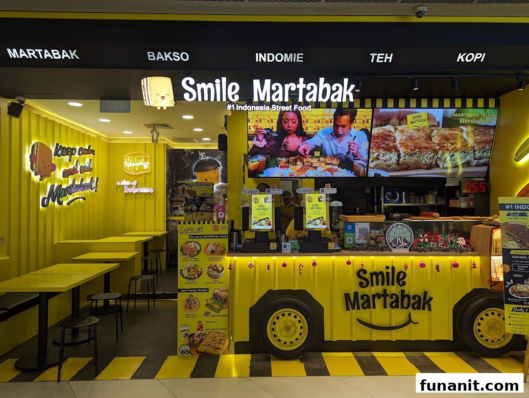 Vibrant yellow Smile Martabak shop front featuring a counter, seating, and screens showcasing Indonesian street food.
