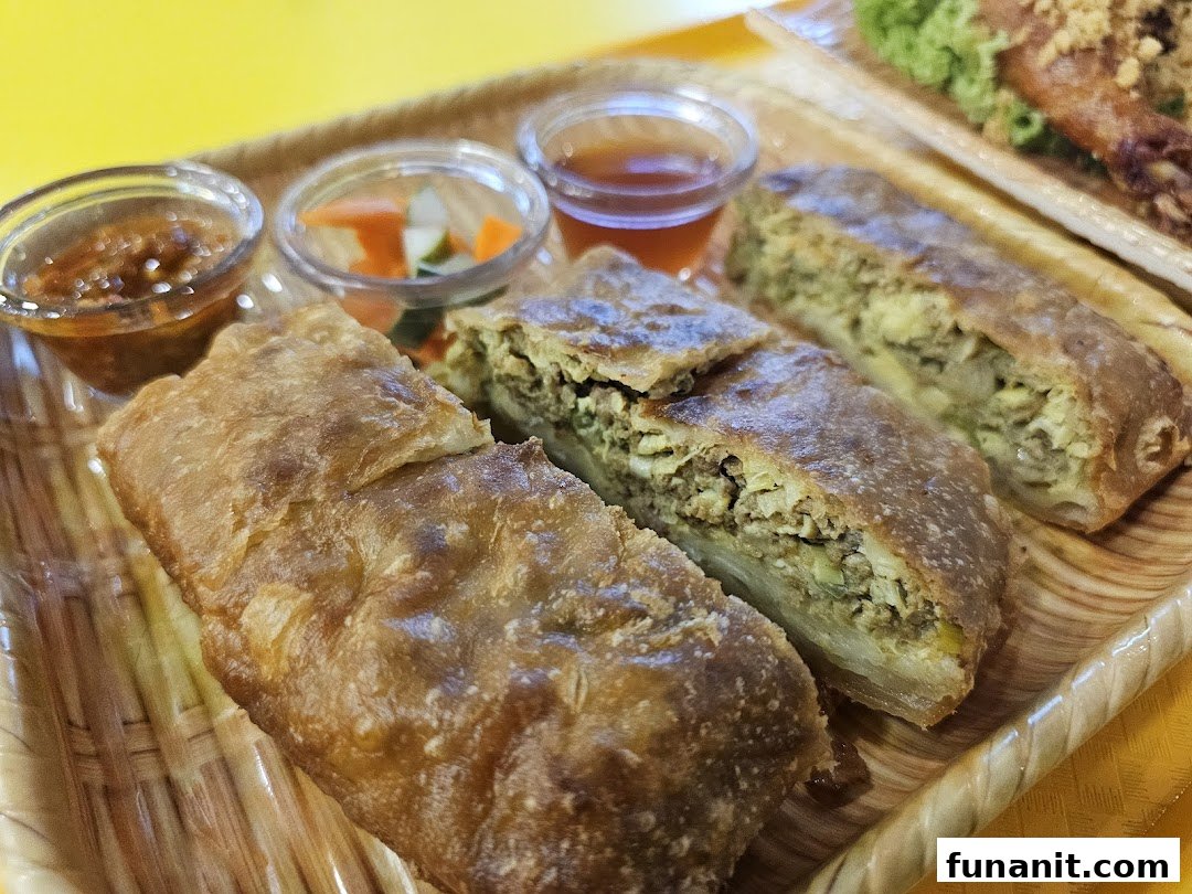 Close-up of savory martabak slices served with chili sauce and pickled vegetables on a tray.