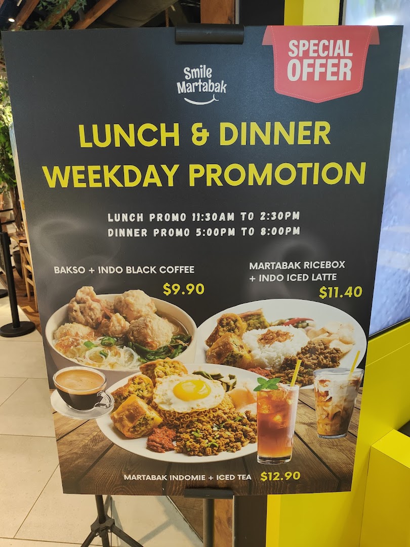 A promotional standee for Smile Martabak's weekday lunch and dinner promotions featuring various Indonesian dishes.