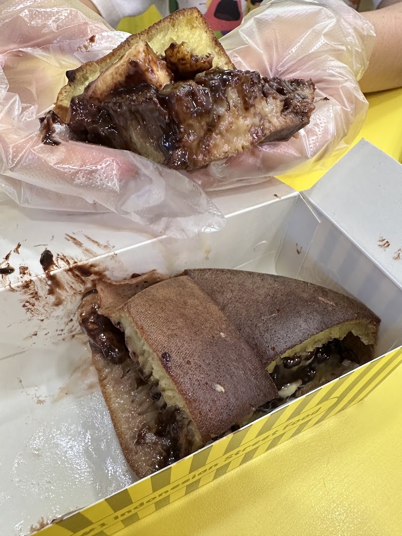 Delicious chocolate martabak being enjoyed, with another piece in a takeaway box.