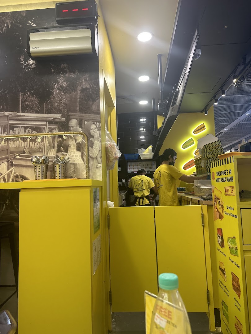 Interior view of Smile Martabak, showing staff preparing food in a vibrant yellow kitchen.