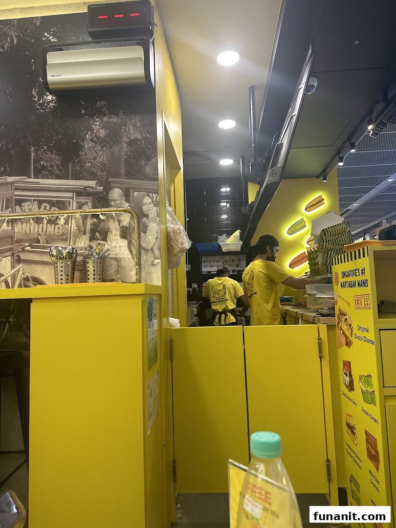 Interior view of Smile Martabak, showing staff preparing food in a vibrant yellow kitchen.