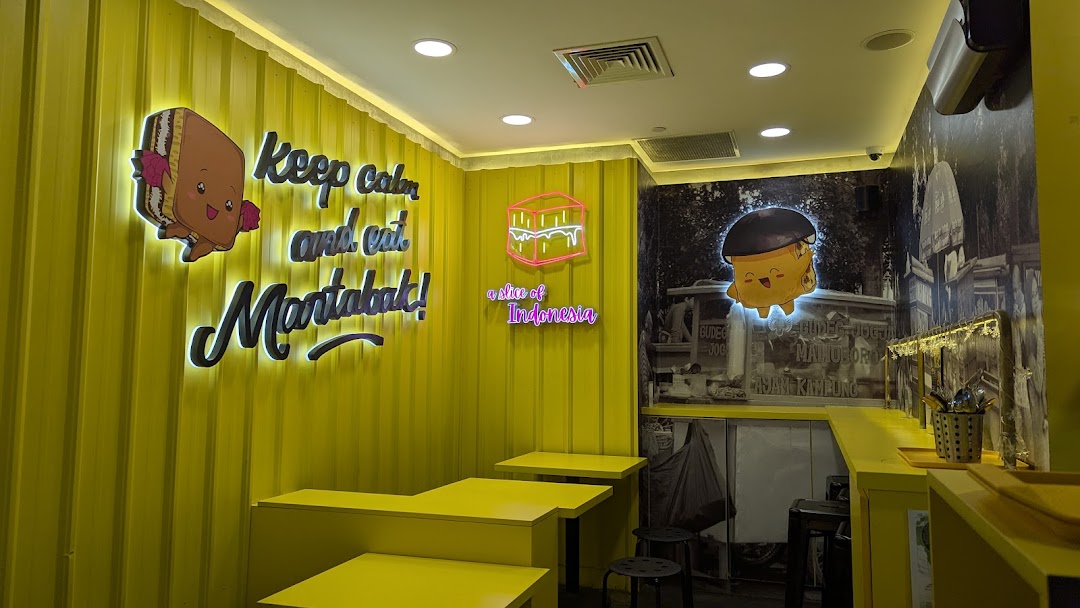 A vibrant interior of Smile Martabak featuring bright yellow walls, playful neon signs, and Indonesian-themed decor.