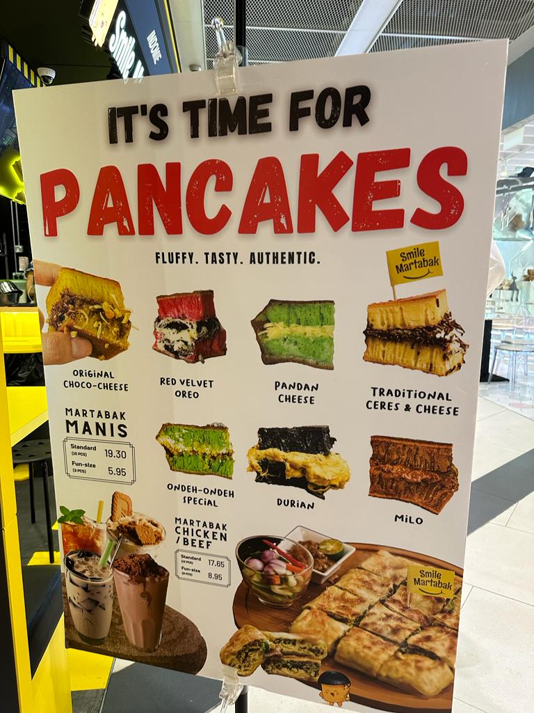 A vibrant menu board showcasing various sweet and savory martabak (pancake) flavors and prices from Smile Martabak.