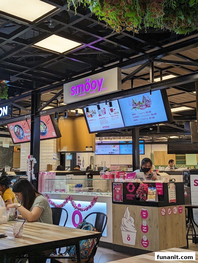 Interior view of smöoy frozen yogurt shop with customers and digital menu screens.