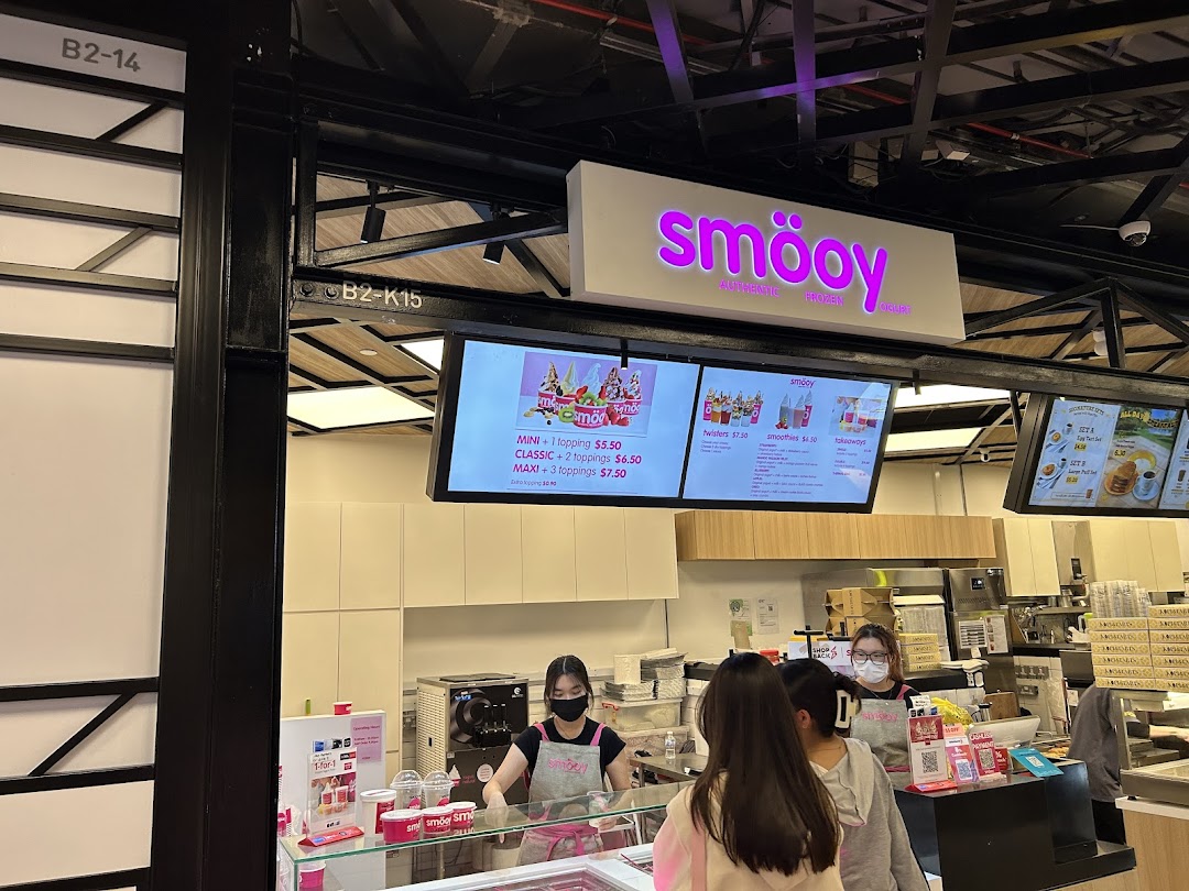 Interior view of smöoy frozen yogurt shop with staff, customers, and digital menu boards.