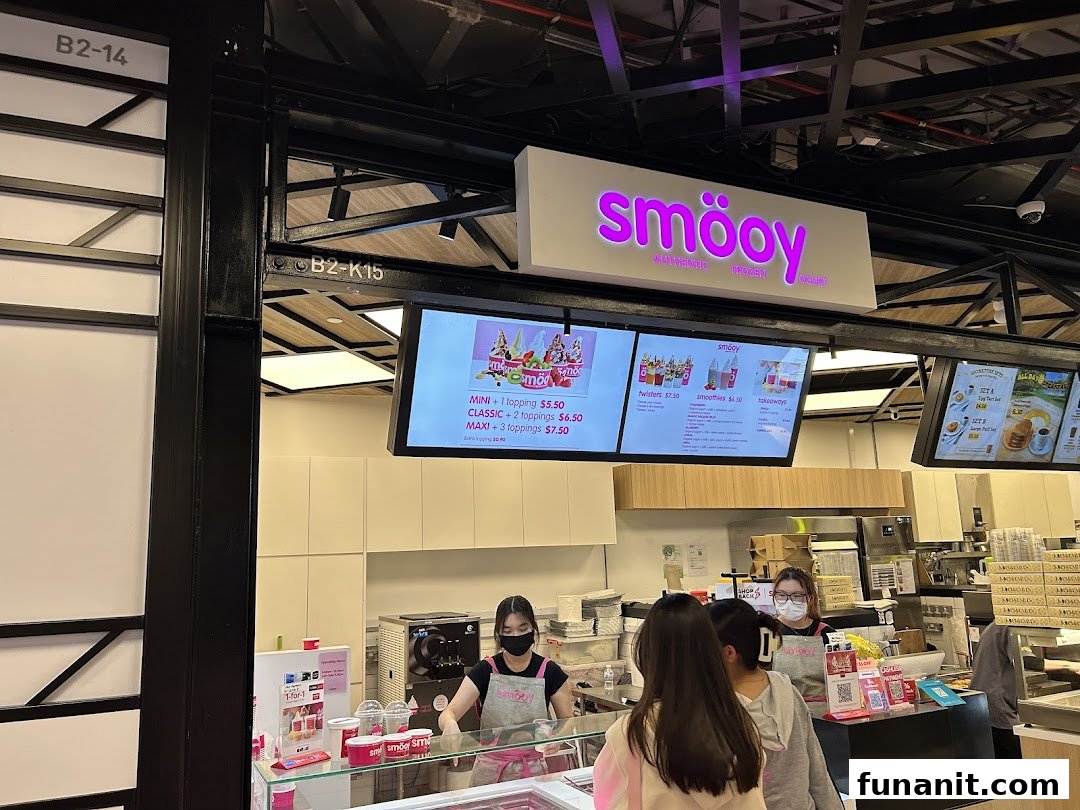 Interior view of smöoy frozen yogurt shop with staff, customers, and digital menu boards.
