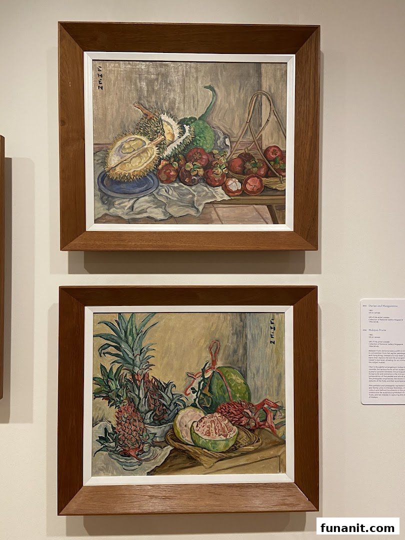 Two framed still-life paintings of tropical fruits displayed on a wall with an information plaque.