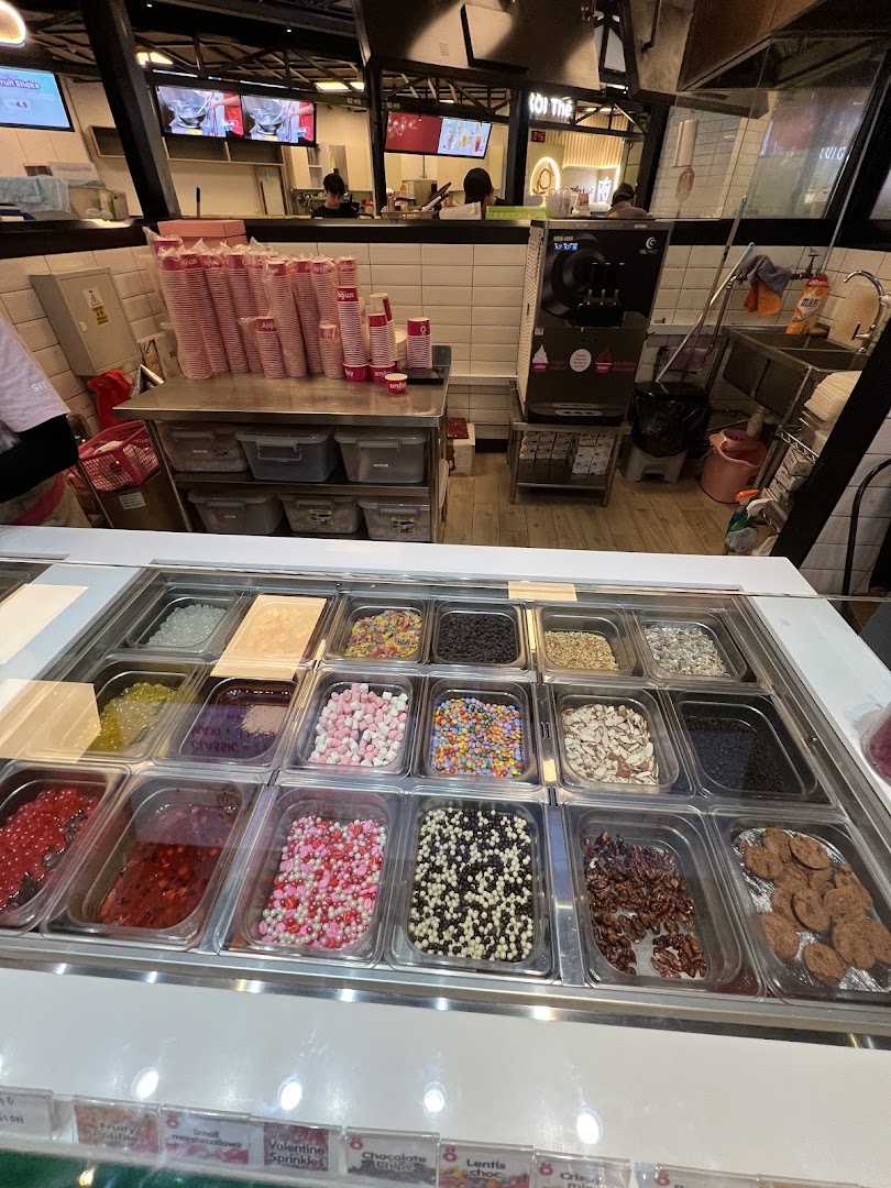 A vibrant display of diverse toppings for frozen yogurt or ice cream at Smöoy, with the service counter visible.