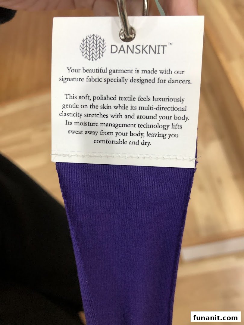 Close-up of a product tag detailing the features of DANSKNIT fabric on a purple garment.