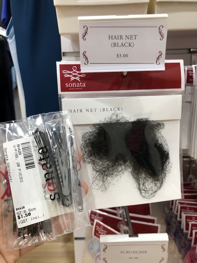 Close-up of Sonata Dancewear hair accessories including hair nets, U-pins, and scrunchies with price tags.