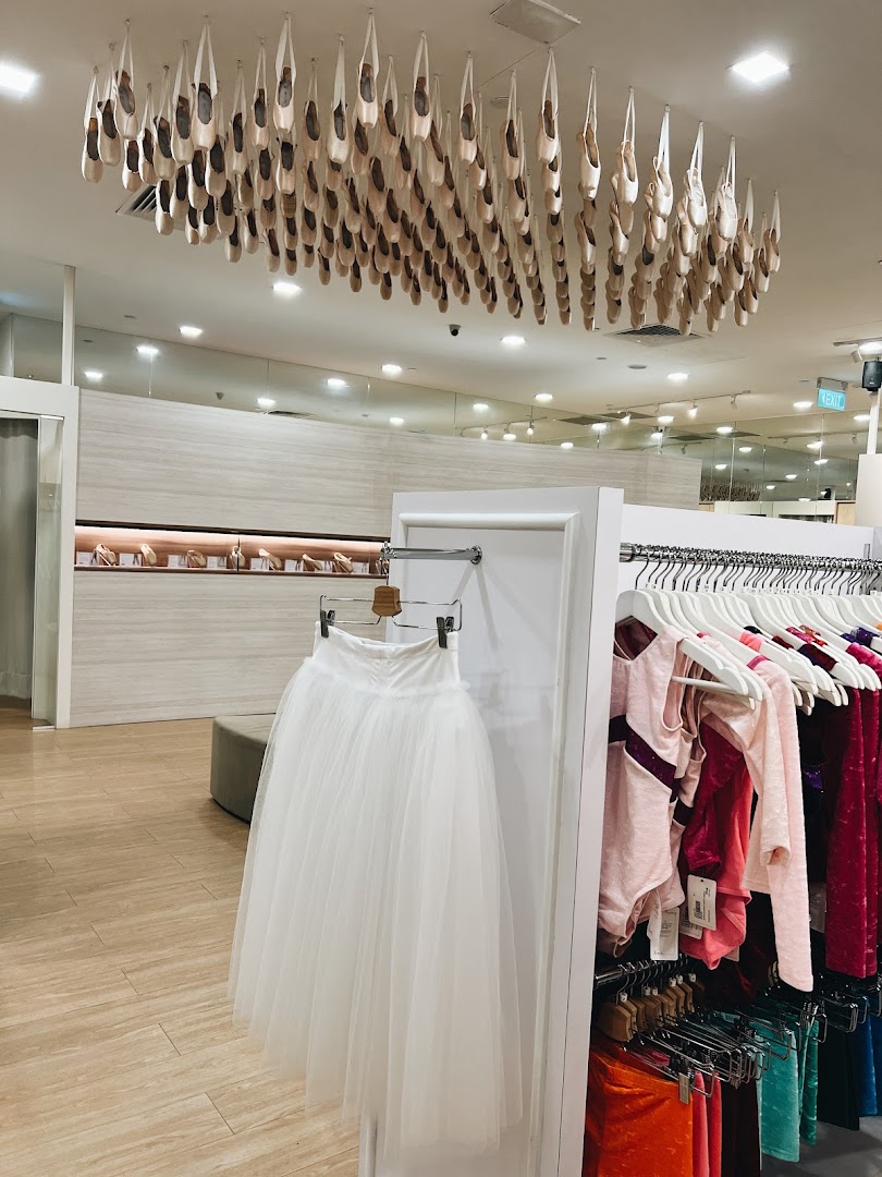 Interior view of Sonata Flagship Store featuring a unique ceiling display of pointe shoes, a white tutu, and colorful dancewear.