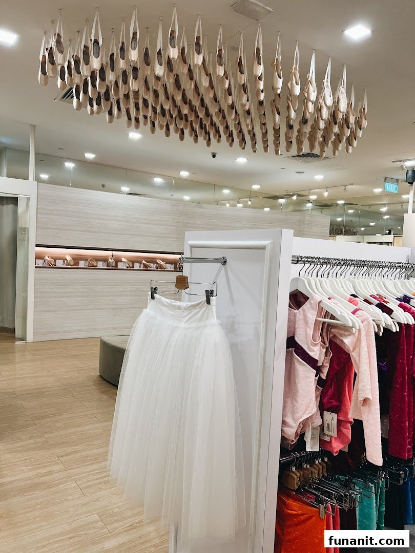 Interior view of Sonata Flagship Store featuring a unique ceiling display of pointe shoes, a white tutu, and colorful dancewear.