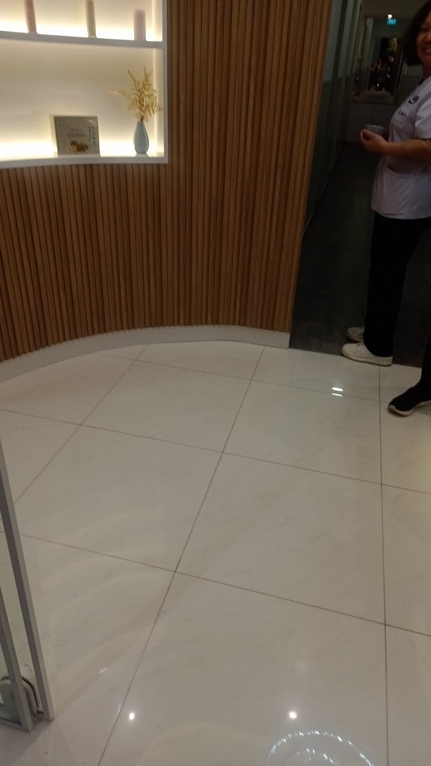 Modern interior with a curved wooden slatted wall, illuminated shelf, white tiled floor, and a staff member.