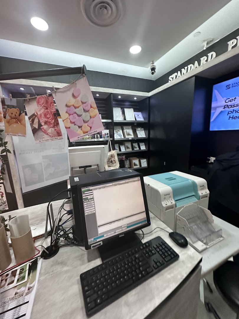A photo printing service counter with computers, printers, and sample prints at Standard Photo Funan.