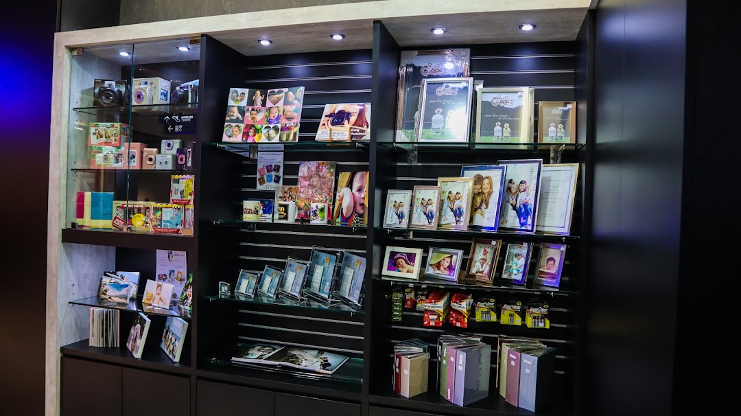 Display shelves showcasing instant cameras, photo frames, custom photo products, and albums at Standard Photo Funan.