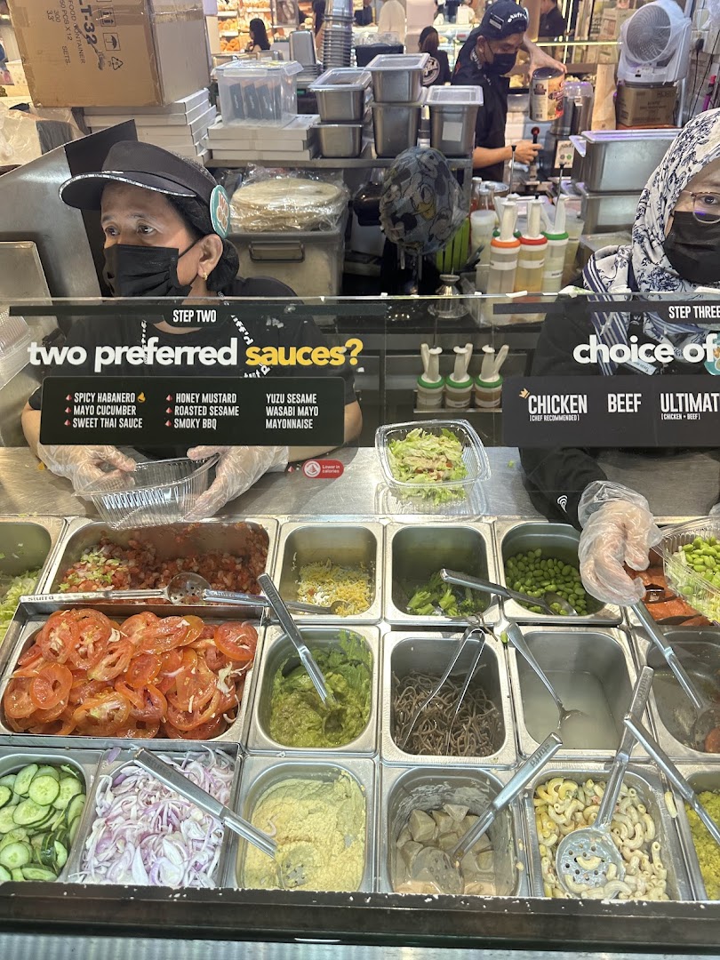 Staff prepare fresh ingredients at Stuffd's vibrant food counter, showcasing customizable meal options.