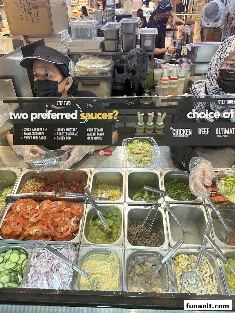 Staff prepare fresh ingredients at Stuffd's vibrant food counter, showcasing customizable meal options.