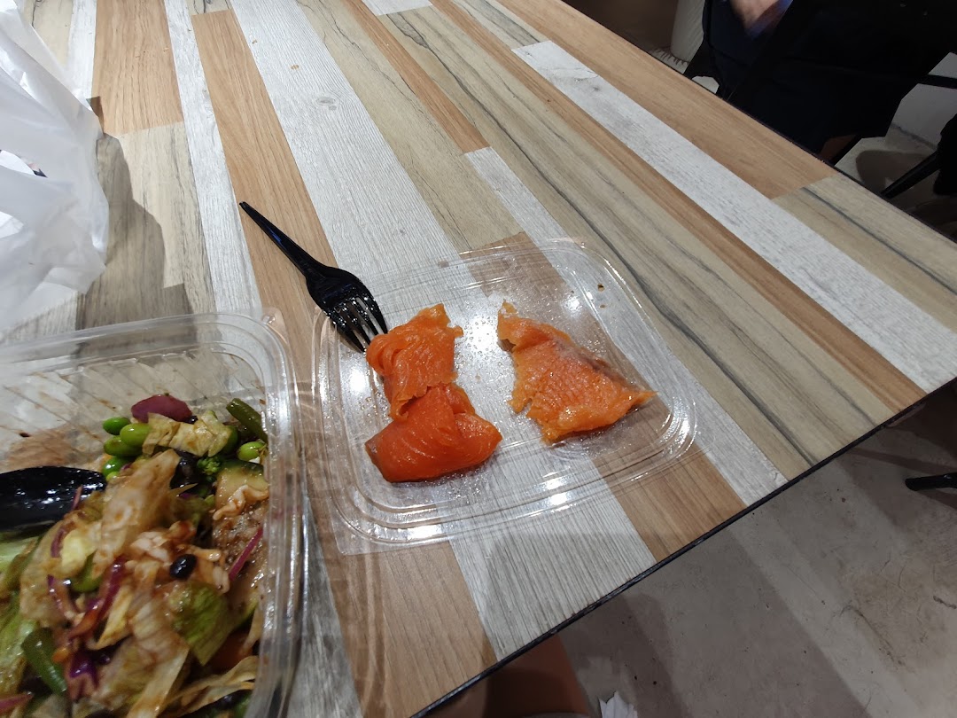 A fresh salad bowl and salmon pieces from Stuffd on a wooden table.