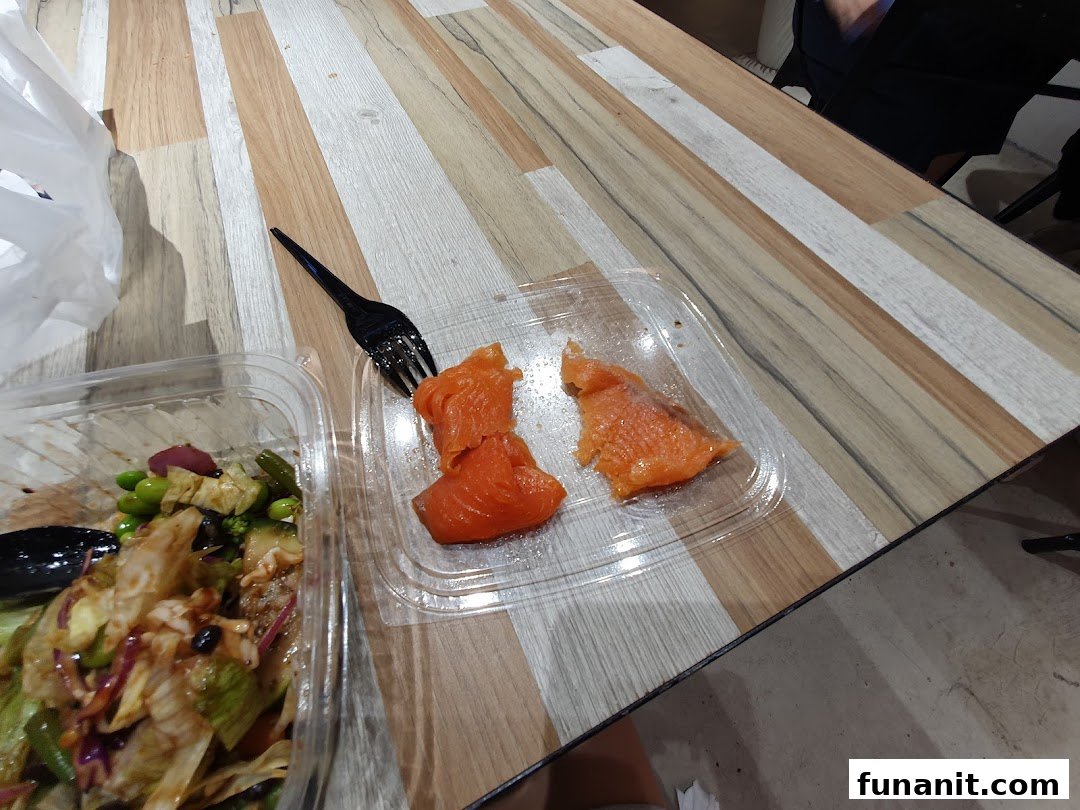 A fresh salad bowl and salmon pieces from Stuffd on a wooden table.