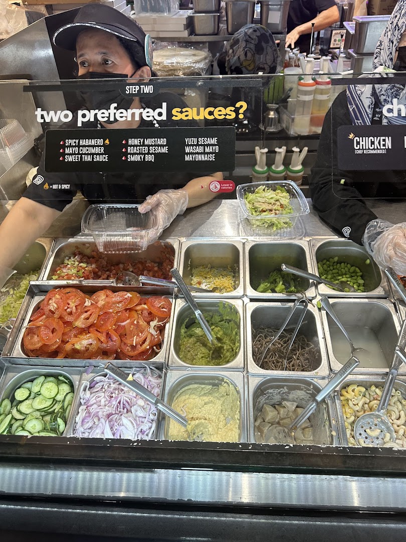 A staff member prepares fresh ingredients and sauces at Stuffd's customizable food counter.