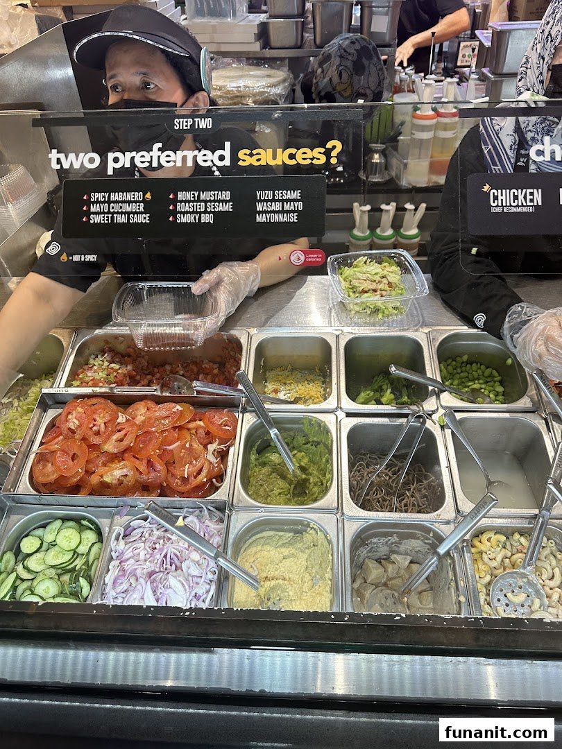 A staff member prepares fresh ingredients and sauces at Stuffd's customizable food counter.