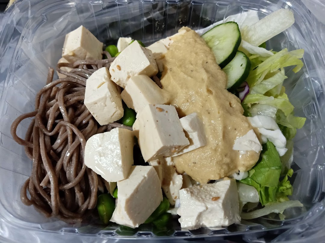 A close-up of a healthy Stuffd bowl with soba noodles, tofu, fresh greens, and creamy dressing.