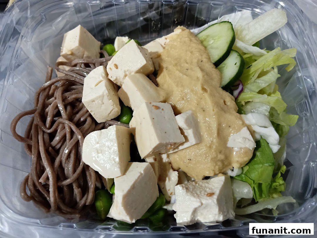 A close-up of a healthy Stuffd bowl with soba noodles, tofu, fresh greens, and creamy dressing.