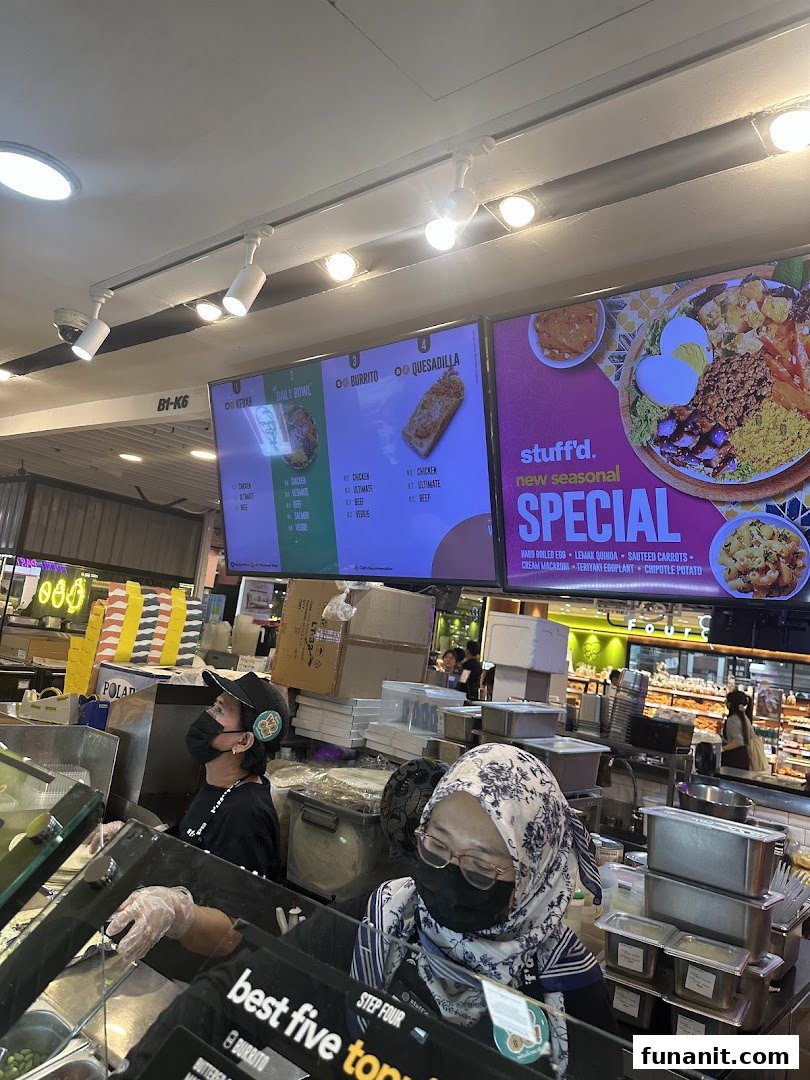 Stuffd's vibrant counter with staff preparing fresh food, showcasing digital menus and seasonal specials.