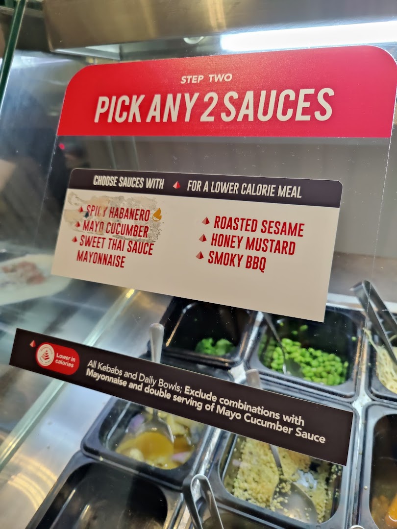 A sign at Stuffd displays sauce options and calorie guidance for custom meals.